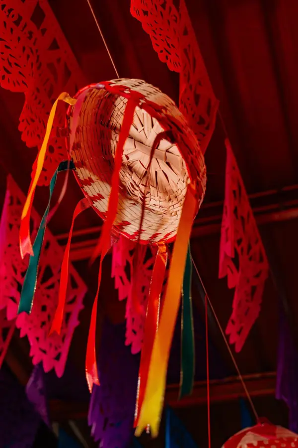 Sombrero de palma con listones entre papel picado rojo